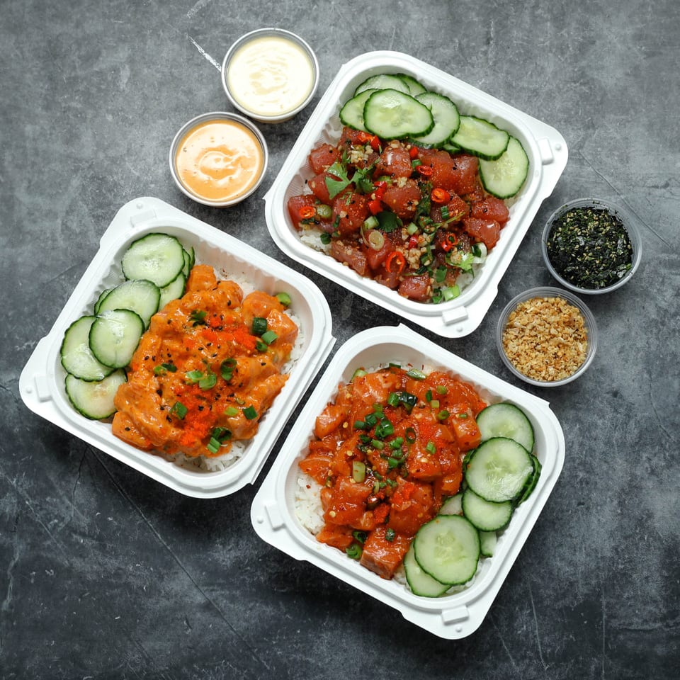 Three takeout bowls contain colorful poke-style dishes with rice, cucumbers, garnishes, sauces, seaweed, and crunchy toppings.